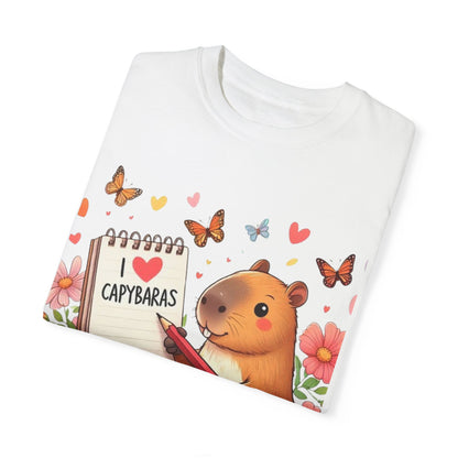 Capibara sosteniendo lápiz y libreta con I Love Capybaras, lindo roedor rodeado de flores y mariposas, camiseta unisex teñida en prenda 